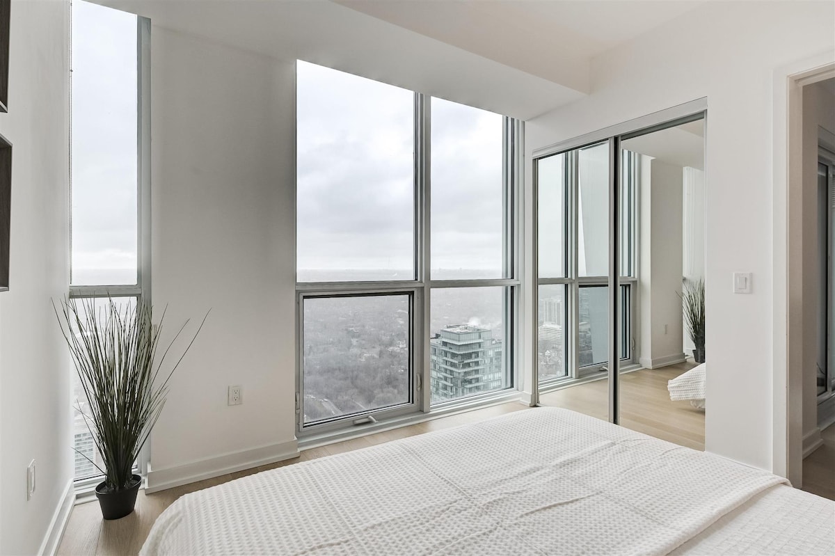 קו הרקיע עם נוף פתוח עם חלונות מהרצפה עד התקרה מחדר השינה.  תיהנו משינה נהדרת עם תריסי גלילה שחורים מותקנים.