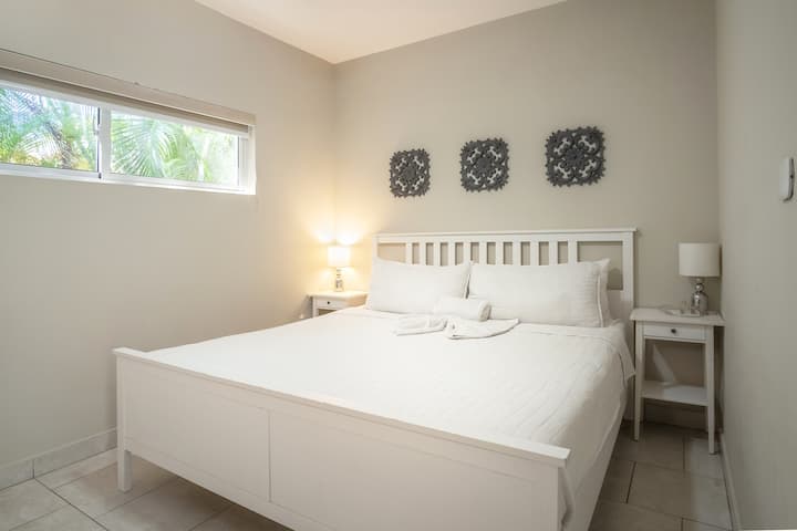 Bedroom 2 with another king-size bed, valet stand for clothes, and a private bathroom just outside the door.