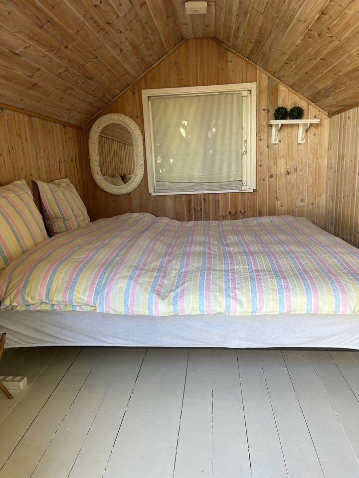 Kiambatisho cha starehe kilicho na kitambaa cha mbao na kitanda cha watu wawili. 