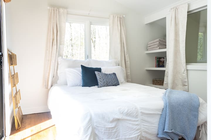 Chumba cha kulala cha roshani kina mlango wa kioo unaoelekea kwenye staha ya kibinafsi inayoangalia ua wa nyuma