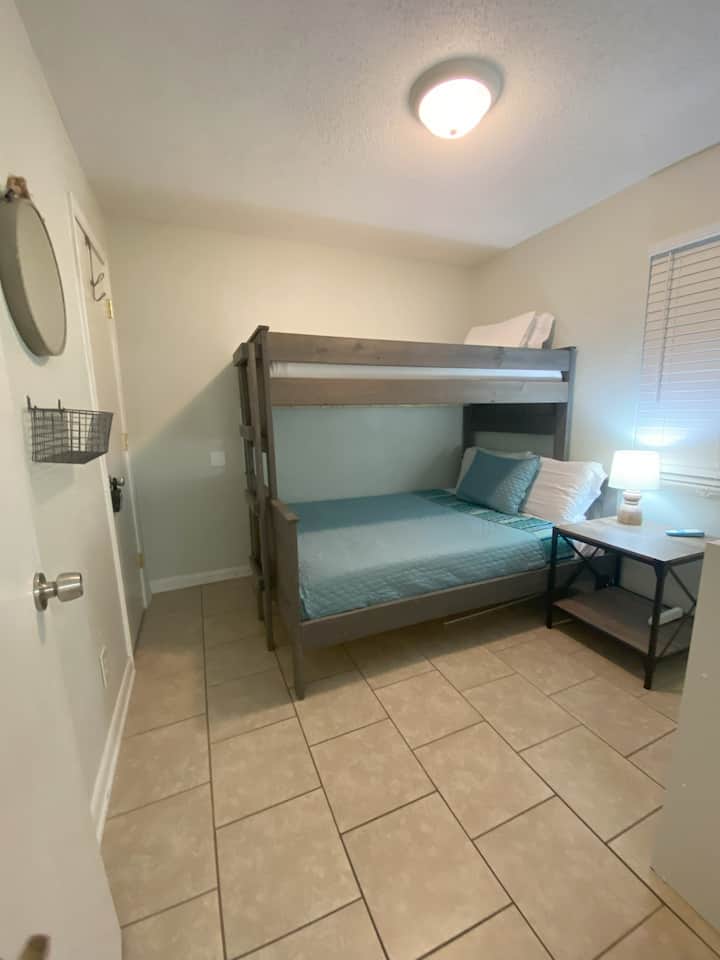 Achterslaapkamer met twee eenpersoonsbedden boven een groot bed. 