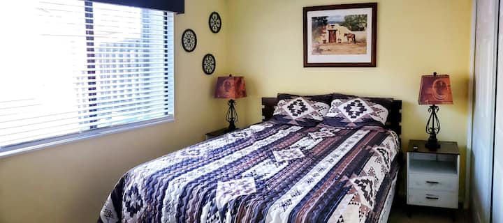 Druga spavaća soba s bračnim krevetom, TV-om, komodom i noćnim ormarićima s hladnim noćnim svjetlom.