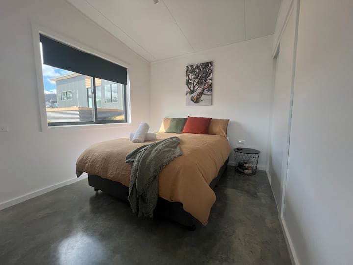 Amplio dormitorio tamaño queen con sábanas de algodón puro, fundas de colchas de lino 100% y edredones de plumas de ganso de origen ético para un sueño cómodo y de fibra natural. Cada habitación cuenta con obras de arte alpinas del fotógrafo local Luke Hasaart.