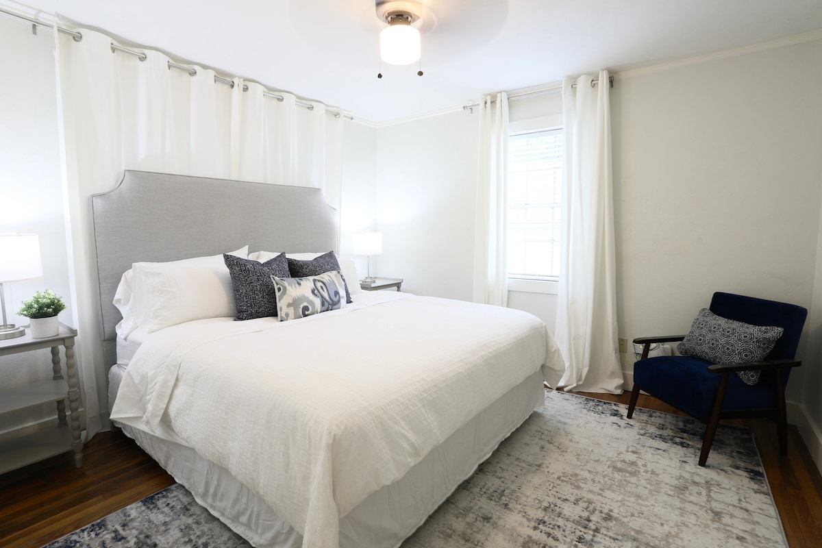 Спокойна спалня, обляна в естествена светлина, с удобно легло с размер King.