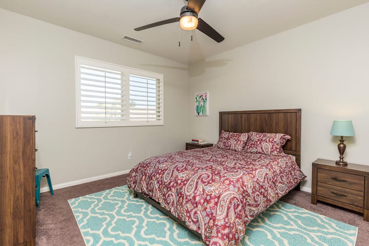 En-suite bedroom with queen size bed and attached bathroom. This room has a dresser, 2 night-stands, and a closet.