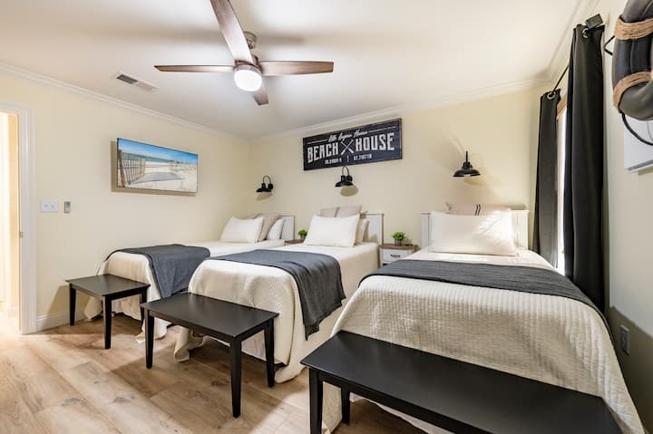 غرفة نوم مريحة على الشاطئ مع ثلاثة أسرّة وديكور بحري ومشاعر مريحة.