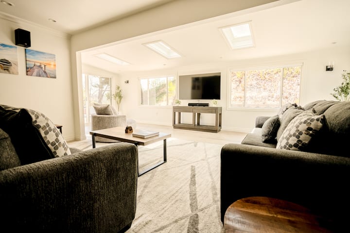 غرفة معيشة مع تلفزيون ذكي 65 بوصة، ومكبرات صوت بلوتوث لتشغيل الموسيقى من هاتفك، وأرائك كبيرة وعناق للاستمتاع بالمناظر.