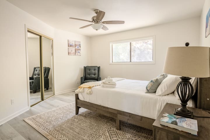 غرفة نوم ثانية بسرير كوين وفراش ميموري فوم وكرسي صالة جلدية وإطلالات على قمة التل