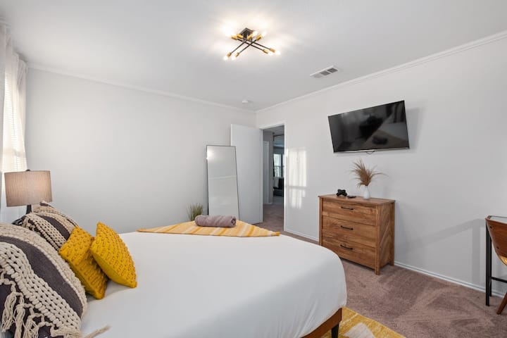 Dhomë gjumi në katin e sipërm me një krevat dopio "queen", televizor inteligjent, pasqyrë me madhësi të plotë dhe një tavolinë pune.