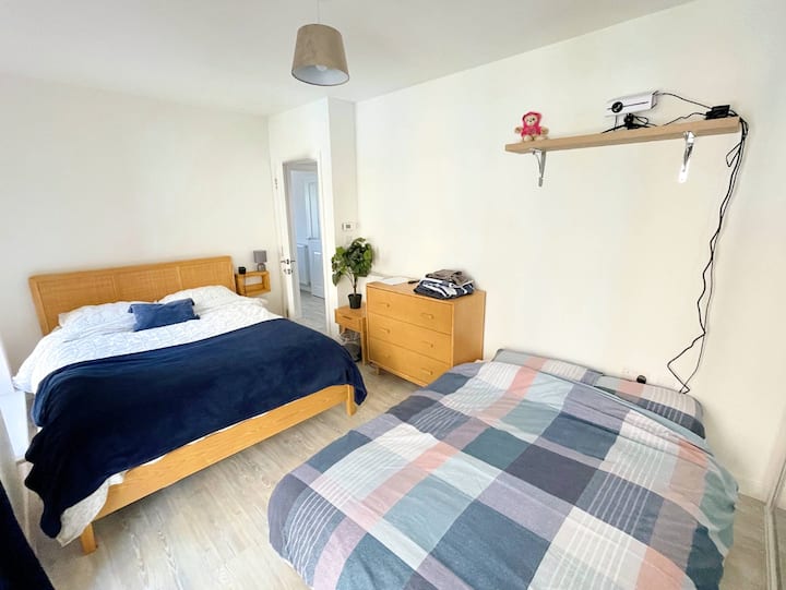 Stort, ljust, rymligt sovrum med en dubbelsäng och en dubbelsäng med massor av förvaring och ett hemmabiosystem