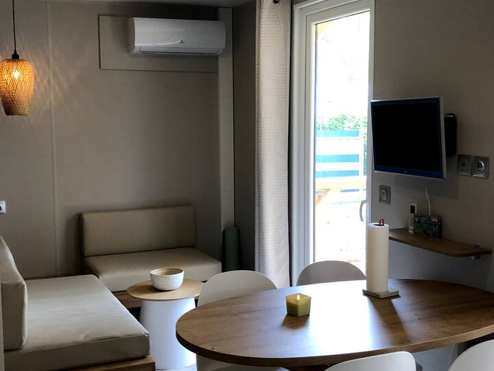 Mesa de comedor y esquina de sofá con aire acondicionado y TV.