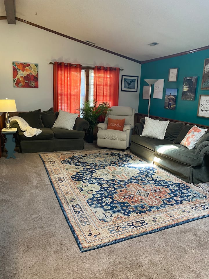 Amplia sala de estar con techo catheral, cómodos sofás y  sillón reclinable.