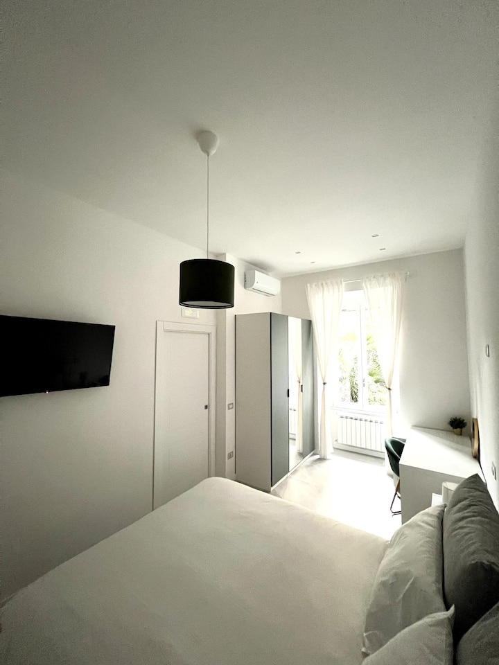 Spavaća soba s pametnim televizorom, kutak za učenje i lijep pogled na dvorište okruženo drvećem