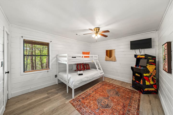 חדר אורחים למטה עם מיטת קומתיים מלאה וארון ארקייד של יום השנה ה -40 של מידוויי, הכולל (Mortal Kombats 1/2/3, Joust, Defender, Rampage, Gauntlet, Paperboy, Rootbeer Tapper, Bubbles, Toobin ו - Wizards of Wor).  טלוויזיה 4K עם אפליקציות!