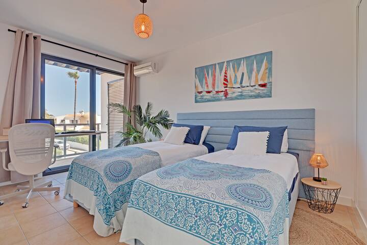 Second bedroom with two single beds with aircon, built in wardrobes and a separate workspace and private terrace at the front.