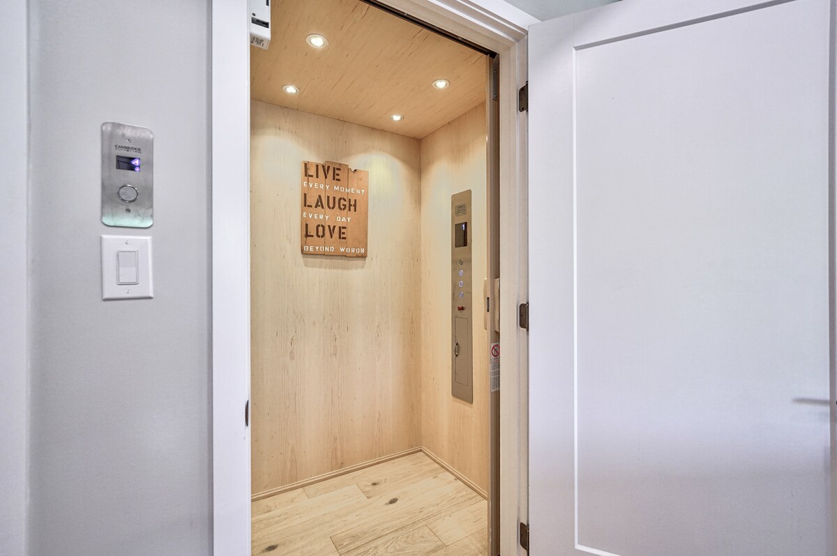 An elegant elevator interior is seen, featuring warm wooden paneling and soft overhead lighting. A motivational wall sign is mounted prominently, while the control panel and options for different floors are visible. The clean and modern design emphasizes accessibility and comfort.
