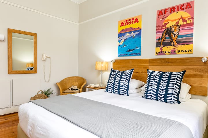 Llamba pranë krevatit me një karrige leximi dhe një tharëse flokësh të montuar.