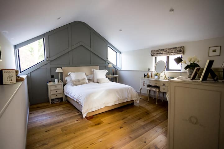 Chambre principale avec lit King Size, linge de lit White Company et fauteuil confortable pour se détendre