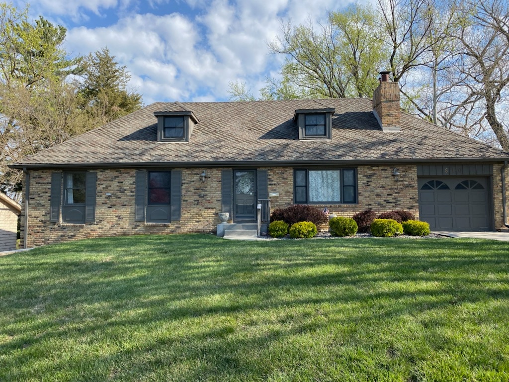 A charming single-story home is presented with a brick exterior and a sloped roof. The front yard features well-maintained green grass and low shrubbery. Large windows allow natural light into the rooms, while a garage is visible to the right side of the entrance.