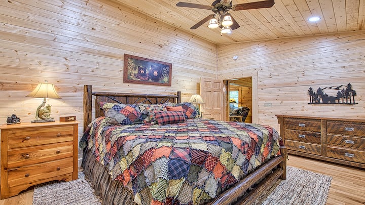 Primary Bedroom, first level of cabin television, dresser, two night stands, walk in closet, and ensuite bathroom.