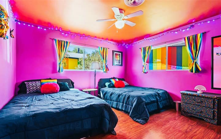 Colorful bedroom with two full beds, dresser, and large closet.