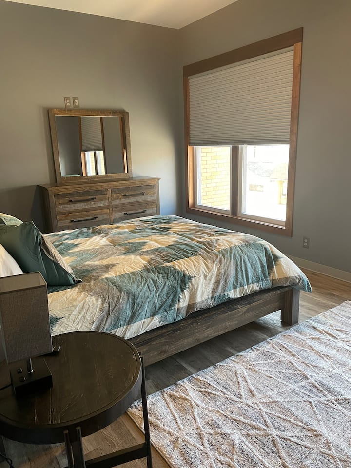 เตียงควีนไซส์พร้อมทีวีขนาด 60 นิ้วพร้อมความสามารถของ Roku ห้องนอนยังมีพัดลมเพดานและม่านบังแสง 