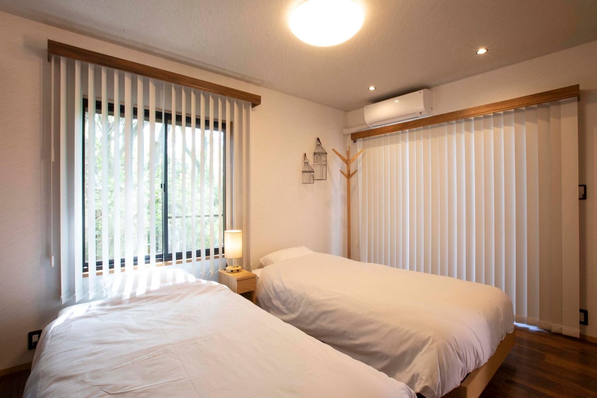 ブラインドから木漏れ日差し込む2ベッドルームの寝室。