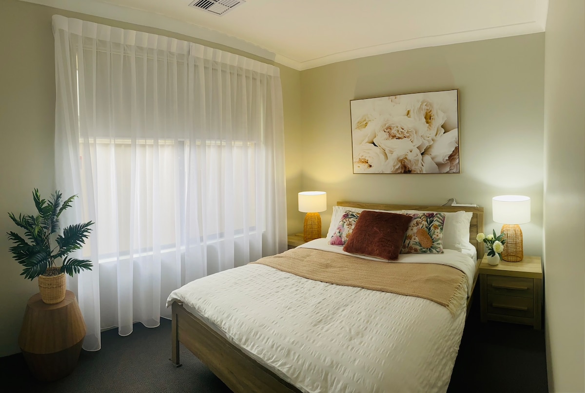 เตียงควีนไซส์แสนสบายพร้อมการตกแต่งที่เป็นกลางและธีมดอกไม้นุ่มๆ