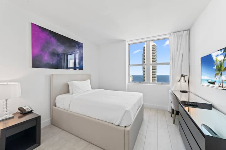 ادخل إلى غرفة النوم الثانية التي تتميز بسرير مزدوج مريح ومرتبة أرضية إضافية للضيوف الإضافيين. تضيف مساحة العمل المخصصة مع المكتب والمصباح الراحة، بينما يضمن الحمام الموجود بجوار الباب سهولة الوصول.