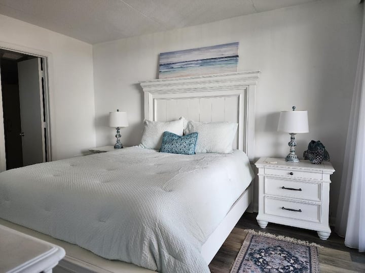 El dormitorio principal tiene una cama tamaño queen con baño privado.  Las mesas de noche tienen lámparas de sensor táctil con puertos USB para la carga del dispositivo.