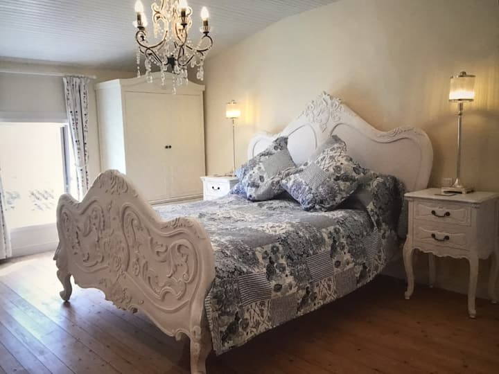 Dhoma elegante e King ensuite ka dy gardëroba të dyfishta dhe duket jashtë në kopshtin e përparmë francez të trëndafilave.