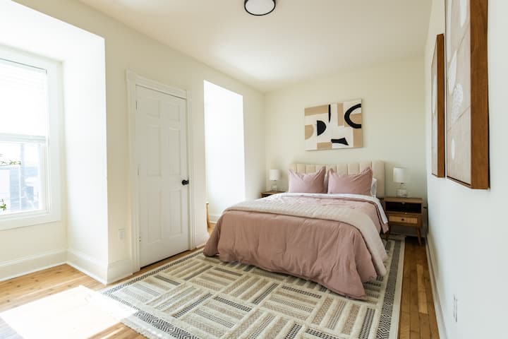 Თანამედროვე საწოლი ბალიშებით, თეთრეულით, ლამპითა და ფანჯრებით