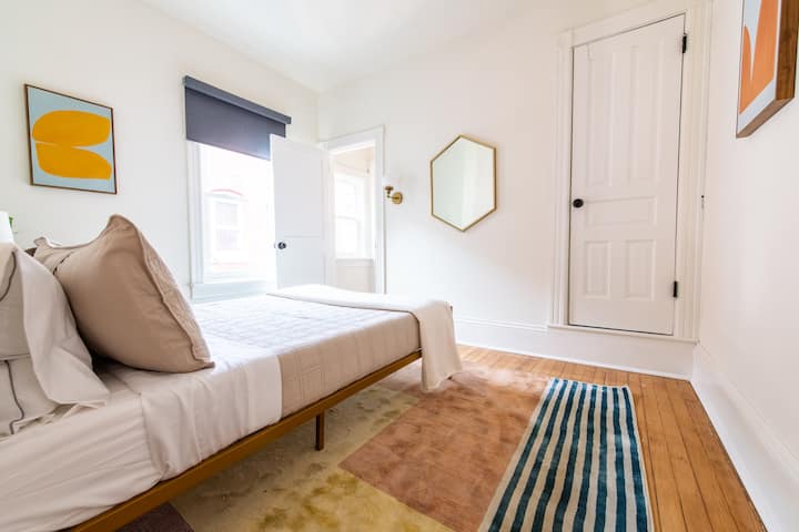 Თანამედროვე საწოლი ბალიშებით, თეთრეულით, ლამპით, სარკითა და ფანჯრებით