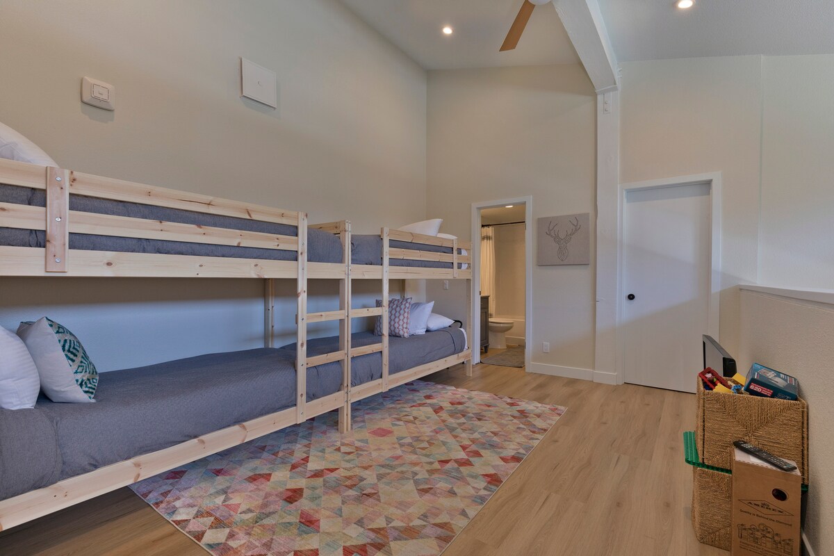 Lofted bunkbed space with attached bathroom, kids' toys, TV and games.
