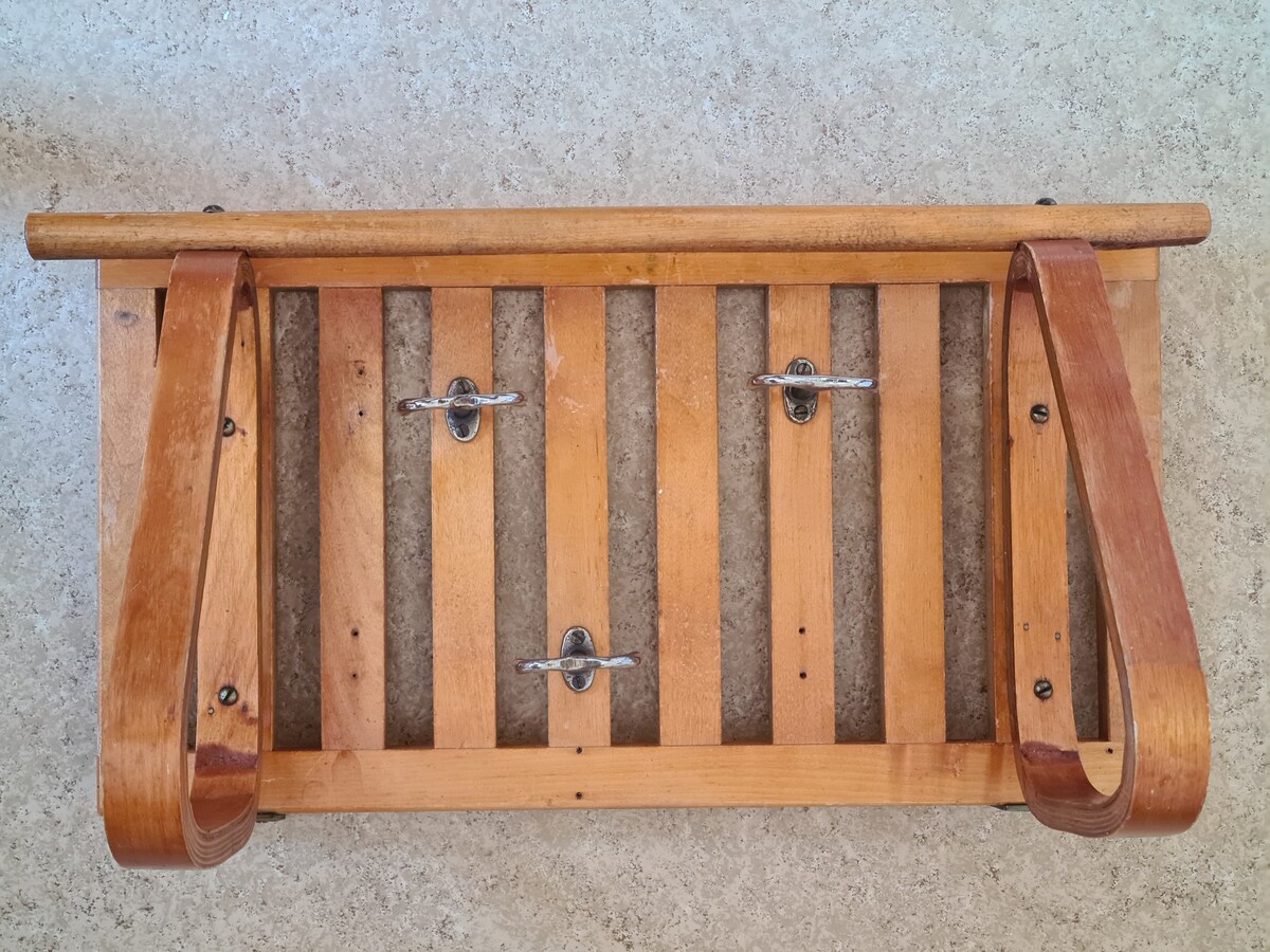 A wooden bench with a slatted design is displayed from above. It features curved armrests and is secured with metal fasteners. The natural wood finish highlights the craftsmanship of the bench, suitable for both indoor and outdoor settings.