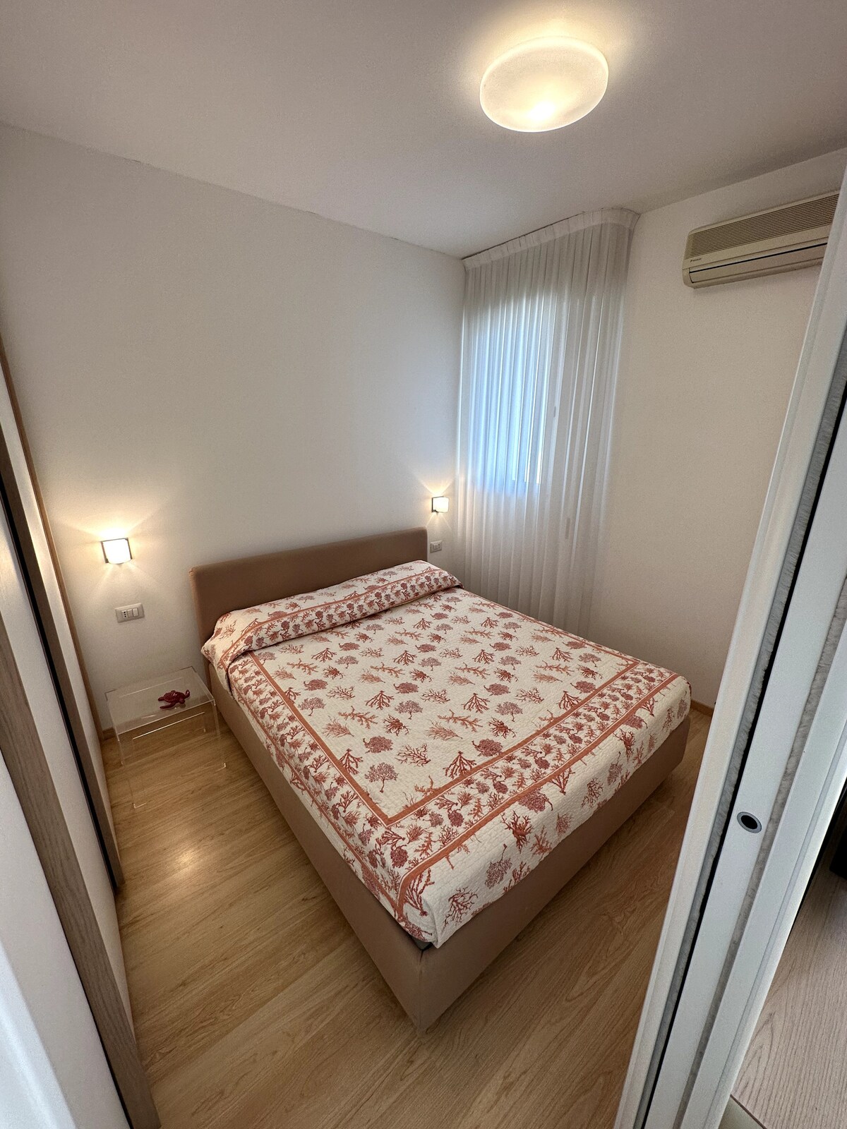 Hlavná spálňa s manželskou posteľou a oknom s výhľadom na more, veľká vyhradená skriňa.