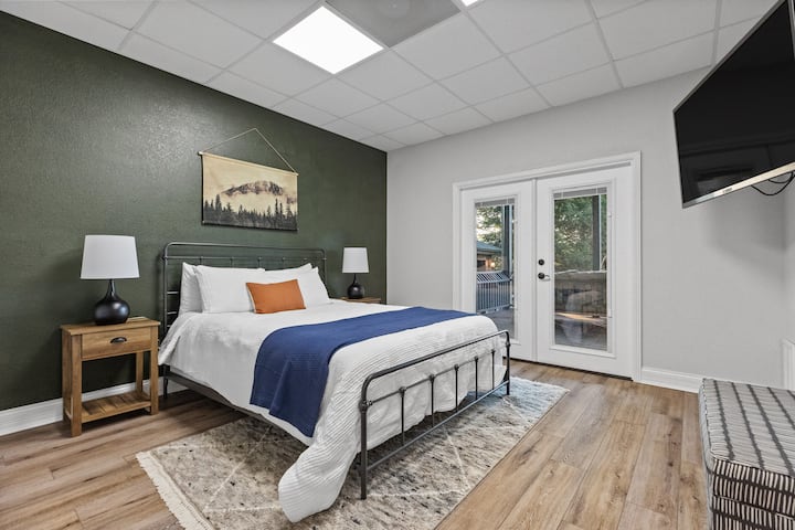 Kitanda cha Malkia katika chumba chetu cha kulala cha ghorofa ya chini, chenye mlango wa Kifaransa unaoelekea kwenye sehemu ya chini ya sitaha na beseni la maji moto. 