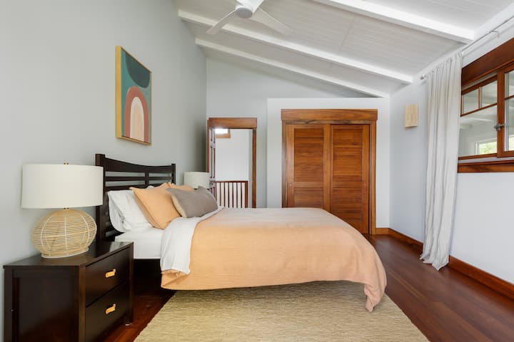 Bedroom 2 features a full sized bed with West Elm duvet. French doors open to the upstairs lanai.