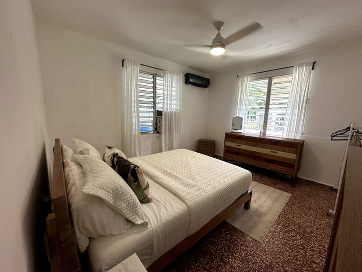 Lit queen size, commode, armoire, placard portable, panier, ventilateur de plafond et climatiseur. 