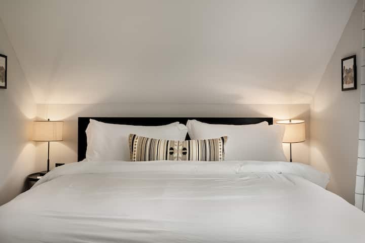 The primary bedroom features a king size bed and side tables with outlets for charging devices.