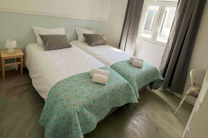Habitación con dos camas individuales, decoración fresca y luminosa, ropa de cama y toallas cómodas incluidas, ideal para una estancia tranquila cerca de la playa.