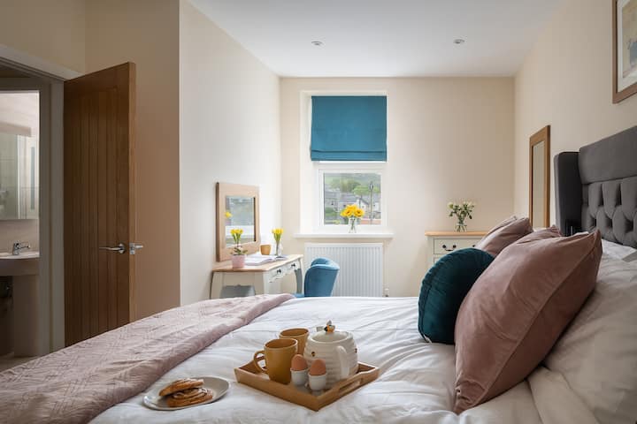 The large king size bedroom has a walk in wardrobe with lots of storage and hanging space plus a bright spacious area for getting ready with a dressing table, chest of drawers and two mirrors.