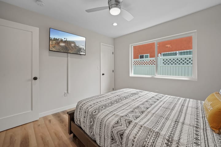 Cozy bedroom with a comfortable bed, smart TV, ceiling fan, and natural light — a peaceful space to recharge after a day in Los Angeles or events at SoFi Stadium.