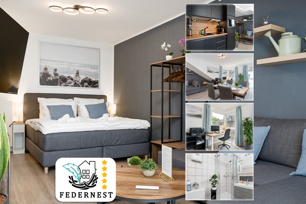 A spacious studio apartment features a comfortable king-size bed accompanied by soft linens. A well-equipped kitchen with sleek cabinetry is showcased, alongside a bright workspace with a monitor and accessories. The cozy seating area invites relaxation, enhanced by natural light from the large window.