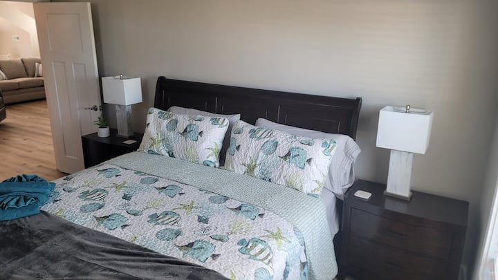 King bedroom with 2 dressers with smart tv and luggage cart . Offering full size mirror and for those late sleepers there are room darkening shades