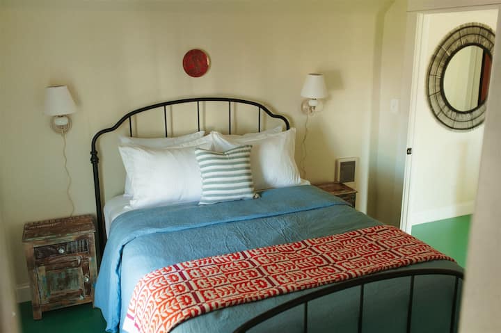 The first bedroom just up the stairs has a queen bed with colorful and comfy Schoolhouse Electric bedding. Organize your belongings in the small closet, keeping everything within reach.