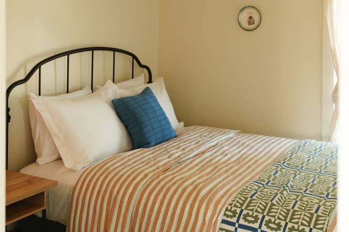 The second bedroom upstairs offers a queen bed and Schoolhouse Electric bedding. Admire the vintage artwork adorning the walls, adding a touch of character and nostalgia to the space.