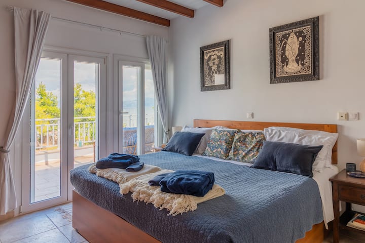 camera da letto con bagno interno e doccia, porte sul balcone con vista sul mare