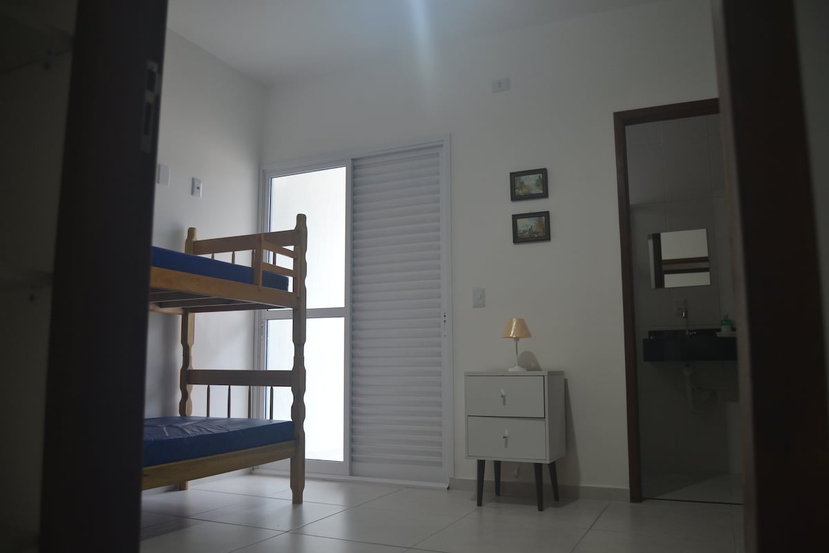 غرفة نوم بسريرين بطابقين وحمام ومروحة سقف وشرفة تطل على حمام السباحة.