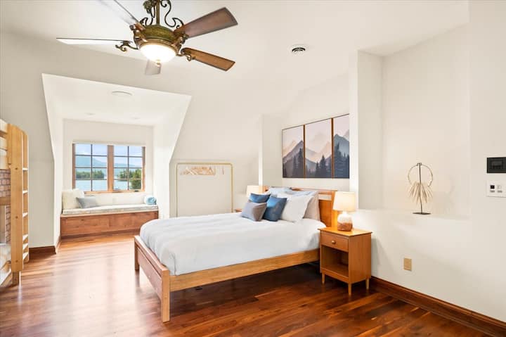 The upstairs features a kid’s den with a full-length window overlooking the lake with two bedrooms on either side. Each bedroom features a queen bed, a twin-over-twin bunk bed, a workspace area, and a half bath.